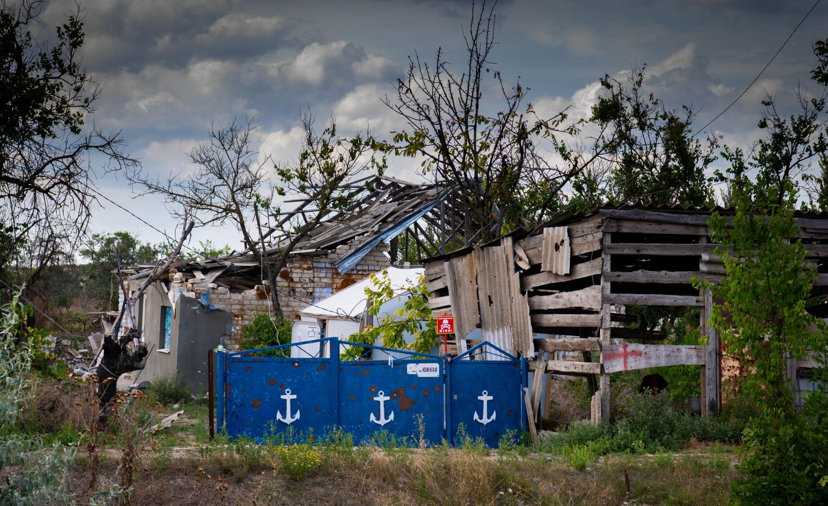 A landmine warning sign behind a fence of a destroyed house in Posad-Pokrovske village, Kherson region