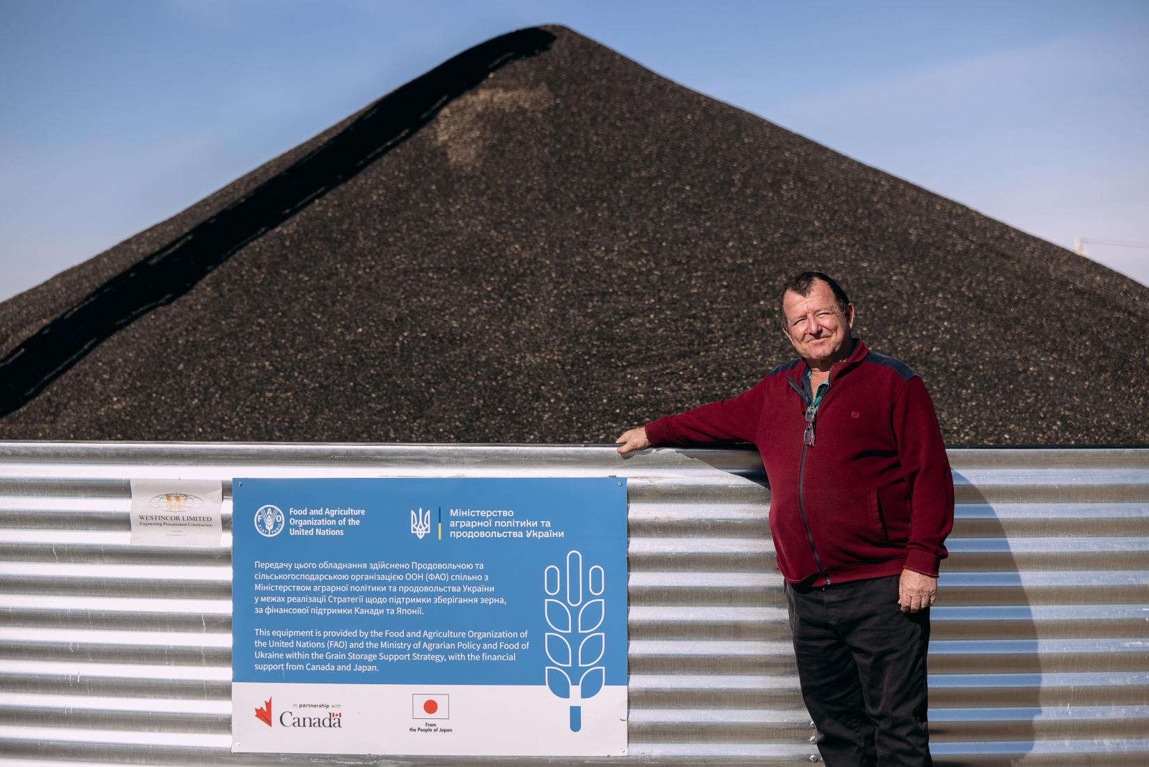 A man standing in front of the grain storage