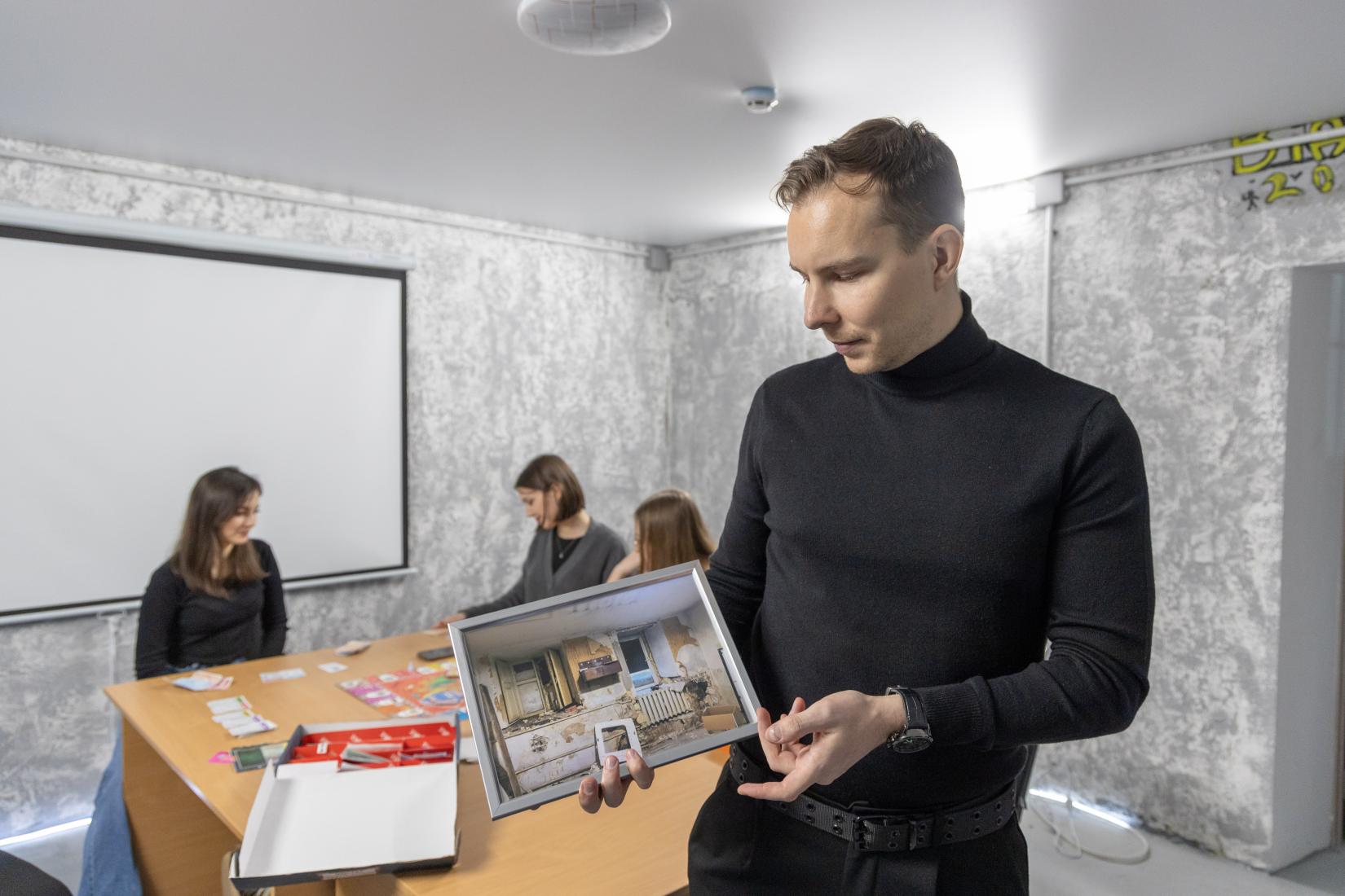 a portrait of man holding a picture of destroyed room