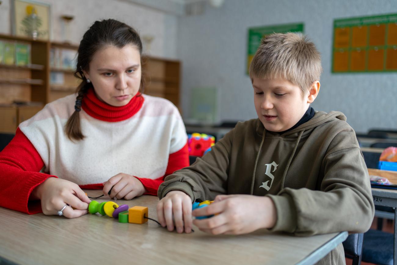 a child with a teacher sitting at the table