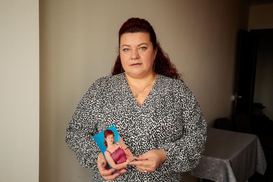 Middle age woman holds a photograph of herself when she was a teenager