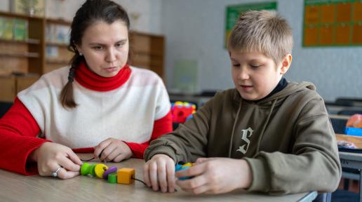 a child with a teacher sitting at the table